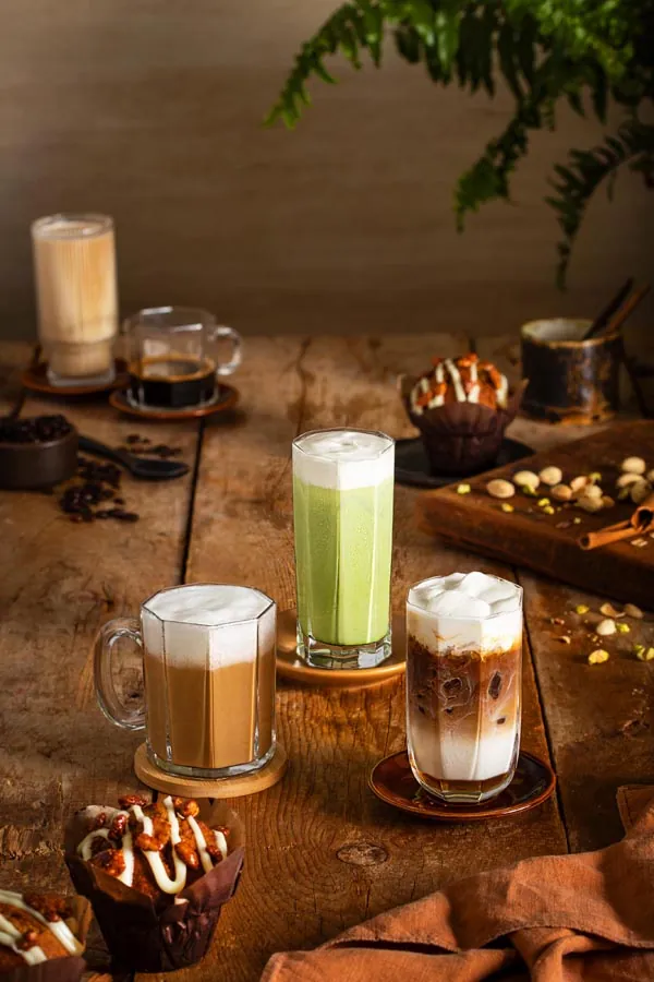 Layered coffee and matcha drinks styled on a cafe table