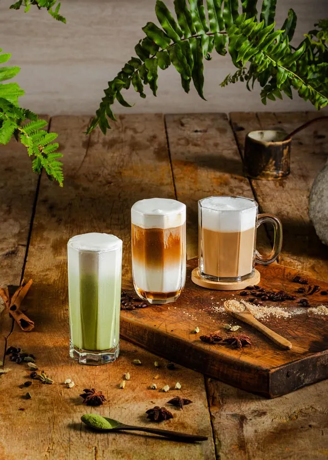Layered coffee and matcha drinks styled on a cafe table